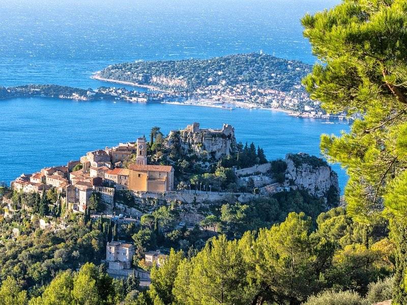 A stone village on a rocky peak above the sea, the coast running away behind it