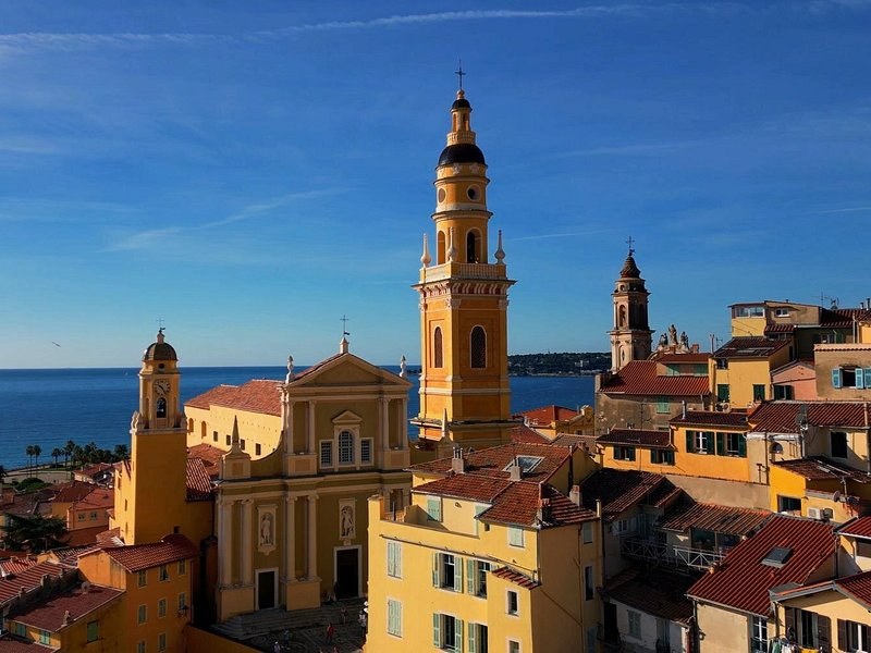 The bell towers of Menton's churches over the old town roofs, the sea behind