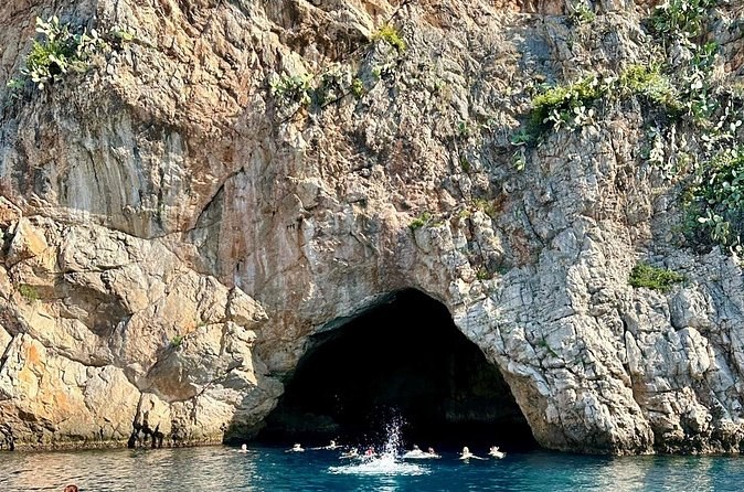 A sea cave at water level in a pale limestone cliff