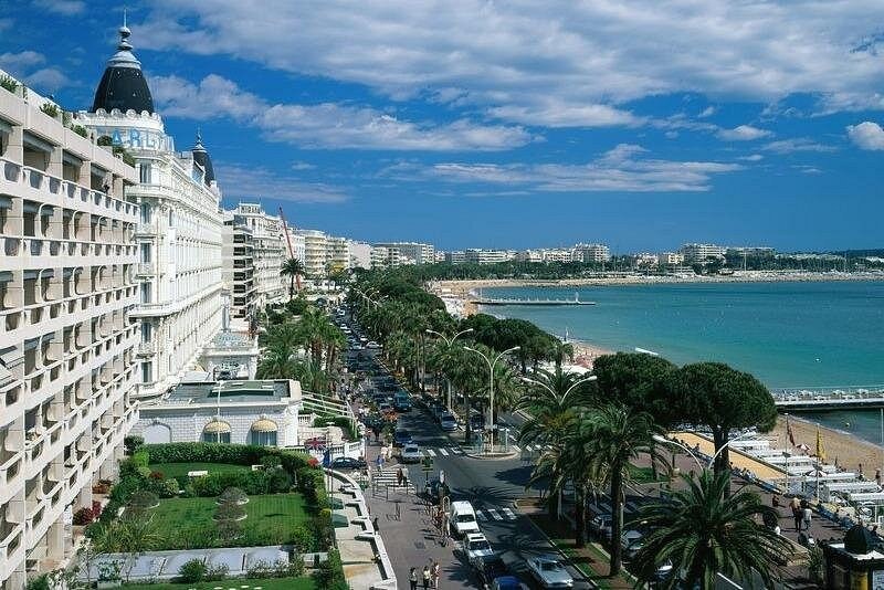 The palm-lined seafront boulevard at Cannes and its beach, seen from above