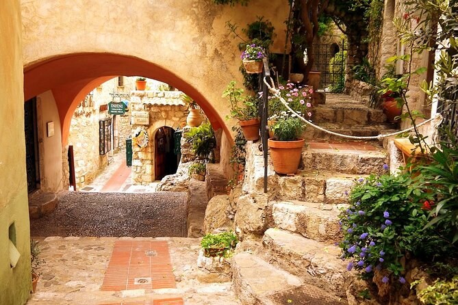 A stone archway, steps and potted flowers in the lane of a hill village