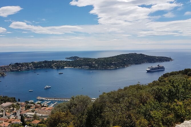 A long wooded cape stretching into the sea, seen from the hills above the bay
